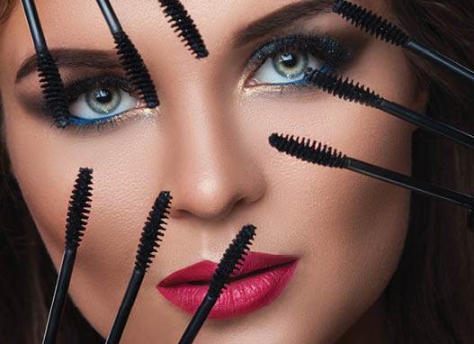 Beautiful woman with beautiful make-up applying mascara on her lashes